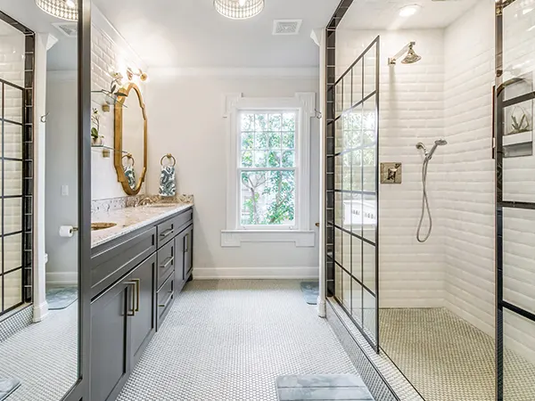 Remodeled bathroom with grey cabinets, white walls and walk in shower.