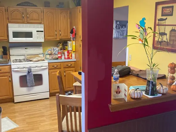 Kitchen view before remodeling with old cabinets and crowded table area