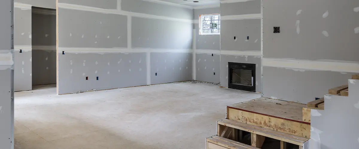 Basement remodel in progress with gray drywall and empty space