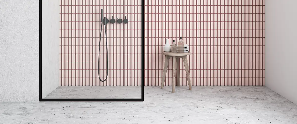 A walk-in shower with pink tile surround and epoxy flooring