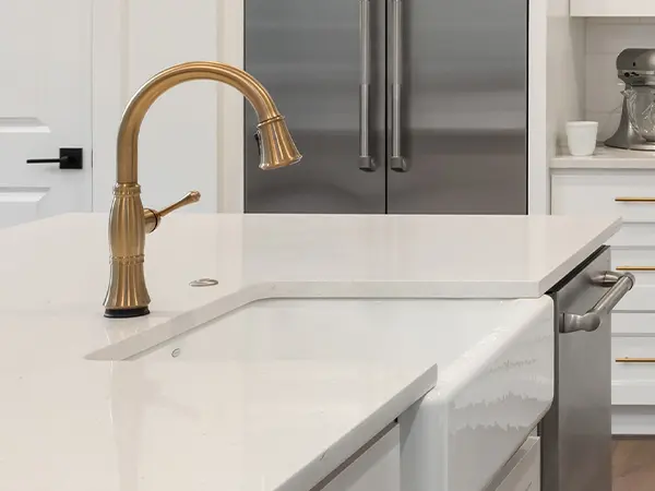 An undermount sink with golden faucet on a marble countertop