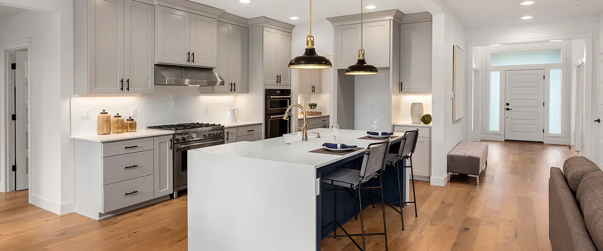 A beautiful, sleek waterfall countertop for a kitchen island in a kitchen with wood flooring