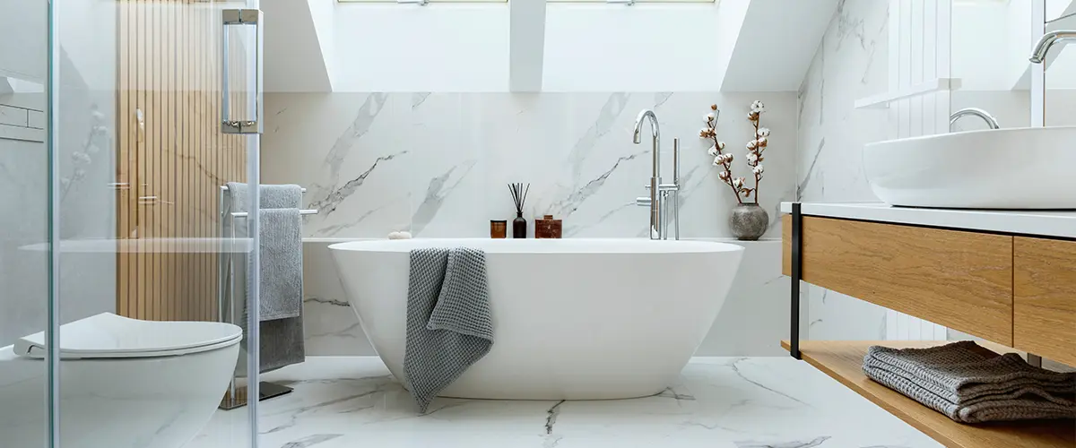 A freestanding tub with marble slabs, glass walk-in shower and a wood vanity