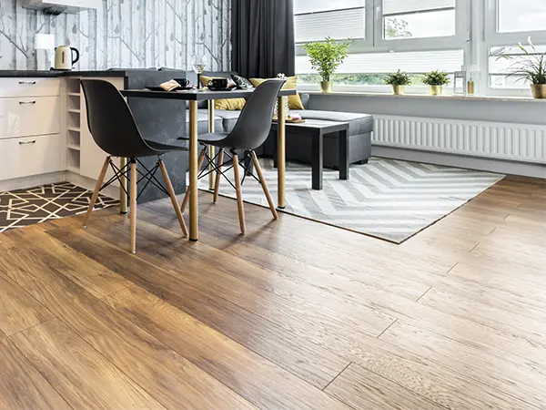 Wood flooring in kitchen with a carpet and a modern table with black chairs
