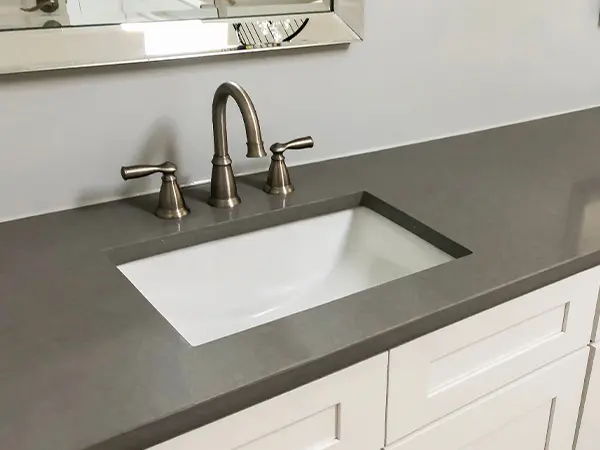A black quart vanity top with a silver faucet