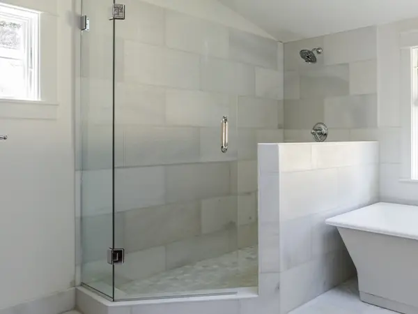 A glass walk-in shower with tiled walls