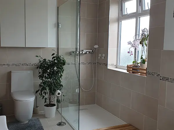 A walk-in shower with a glass panel and pan