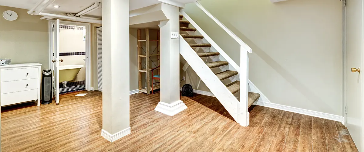 A living room with a bedroom and a half bathroom in a basement