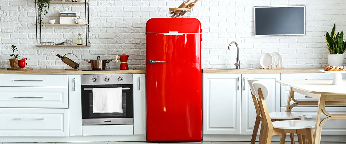 A red fridge and a kitchen range in a kitchen with white cabinets