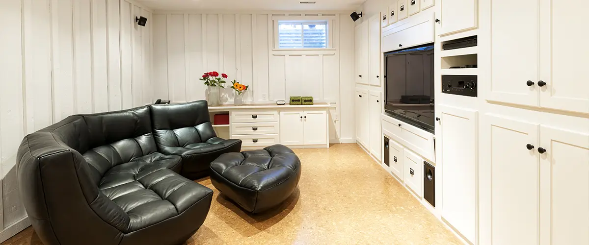 A basement made into a living space with a large couch and a TV