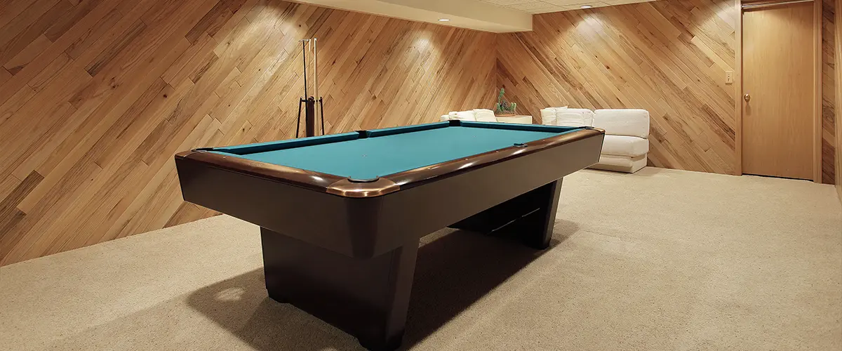 A pool table in a basement with carpet floor