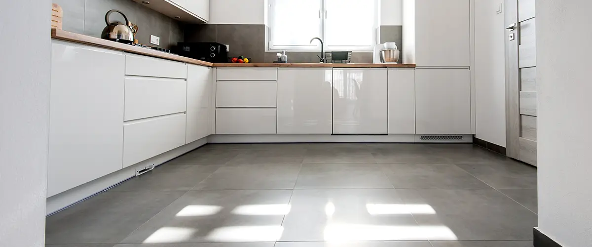 Large gray tile flooring in a modern kitchen with white cabinets