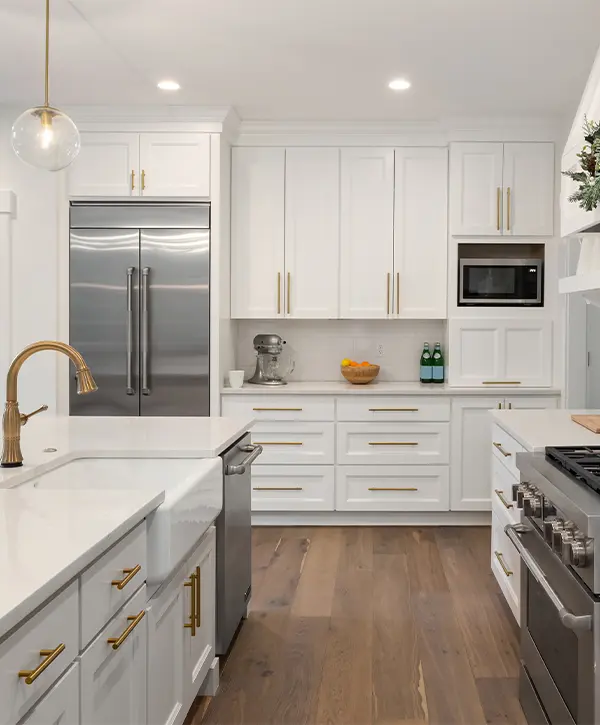White kitchen cabinets with golden pulls and water fixtures