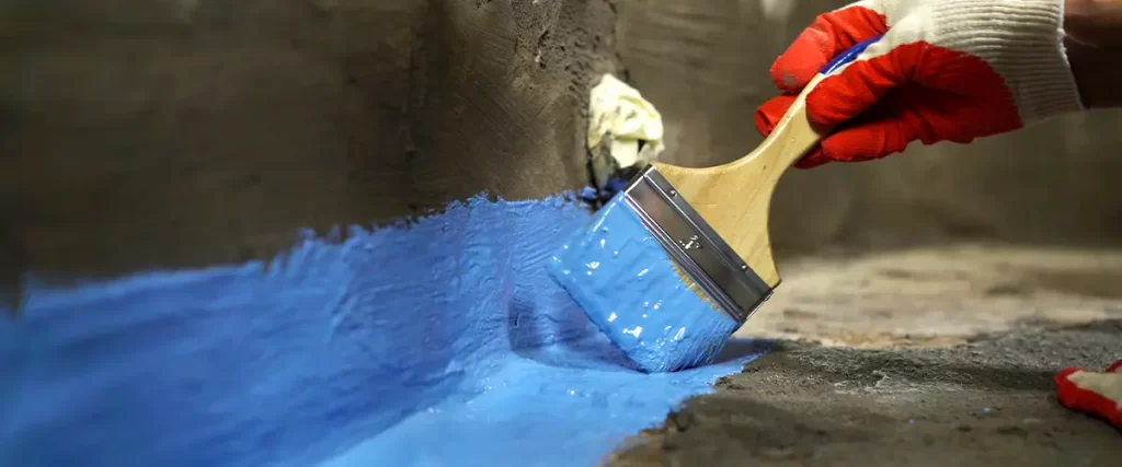 Man Performing Basement Waterproofing with Blue Paint