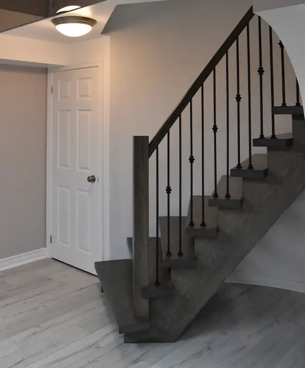 Image of dark wooden stairs leading to a remodeled basement.