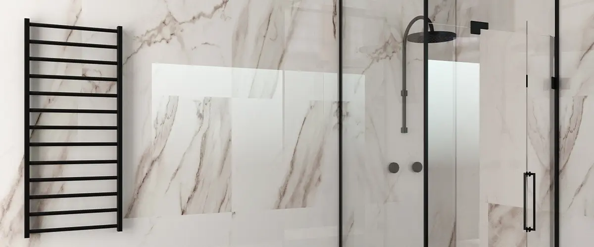 Modern bathroom with marble shower walls, glass shower enclosure, black fixtures, towel rack, and decorative plants on grey tiled floor.