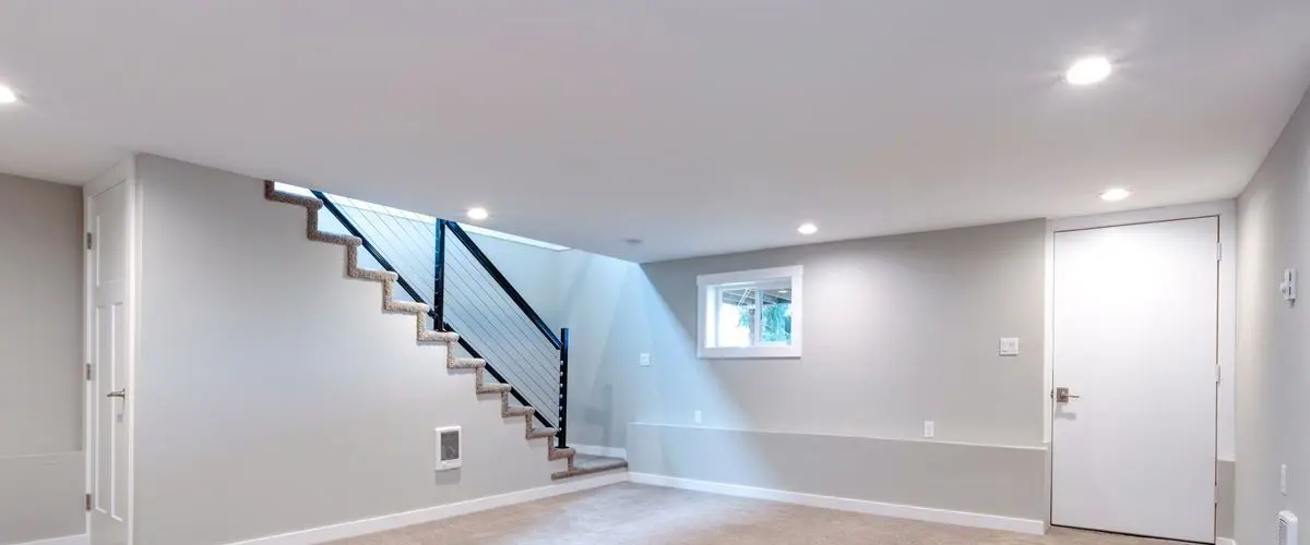 Empty carpeted basement with stairs featuring modern railing, ideal for basement remodeling in Bellevue.