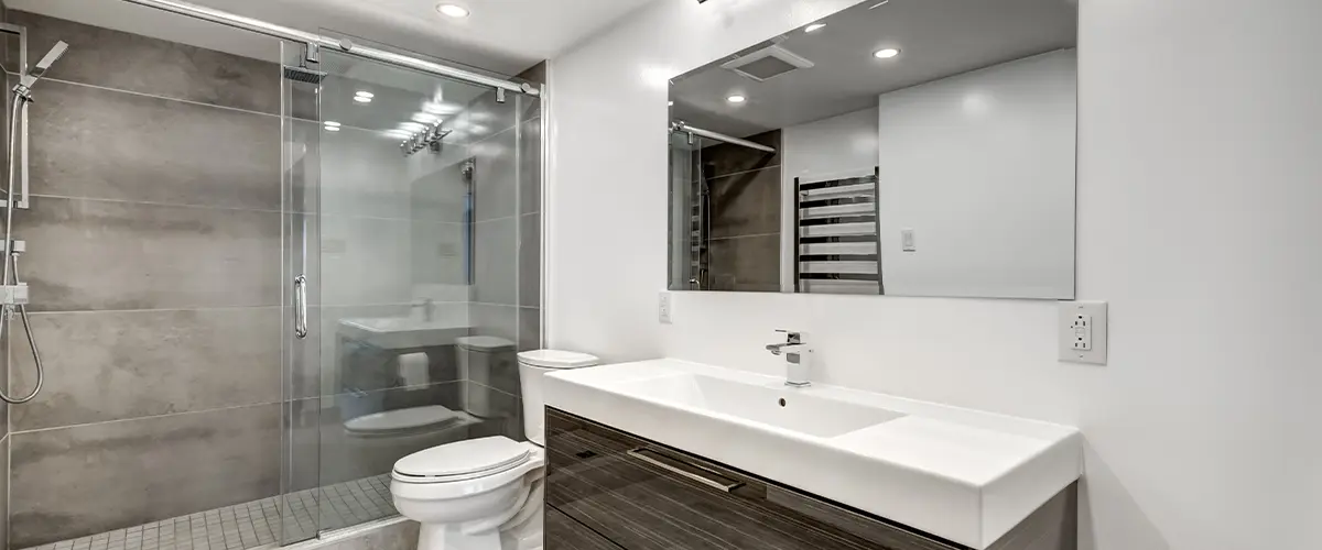 Modern bathroom remodeling in Omaha, with glass shower, sleek dark wood vanity, and bright lighting, perfect for a stylish and functional space.