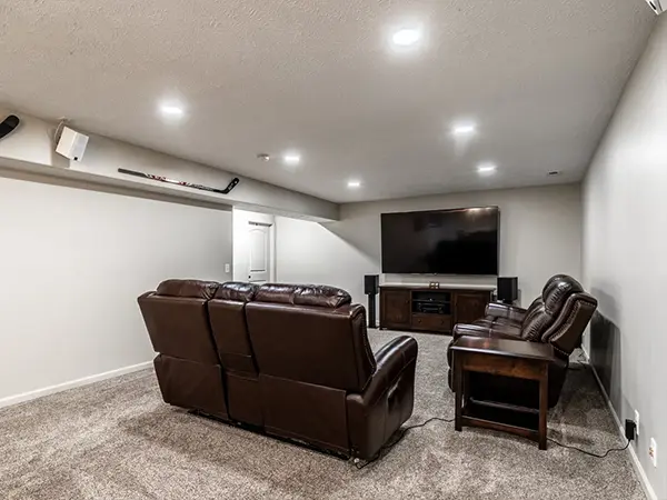 Spacious basement home theater with plush leather seating and large wall-mounted flat-screen TV.