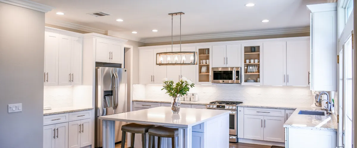 Modern white kitchen with a large island, stainless steel appliances, and under-cabinet lighting