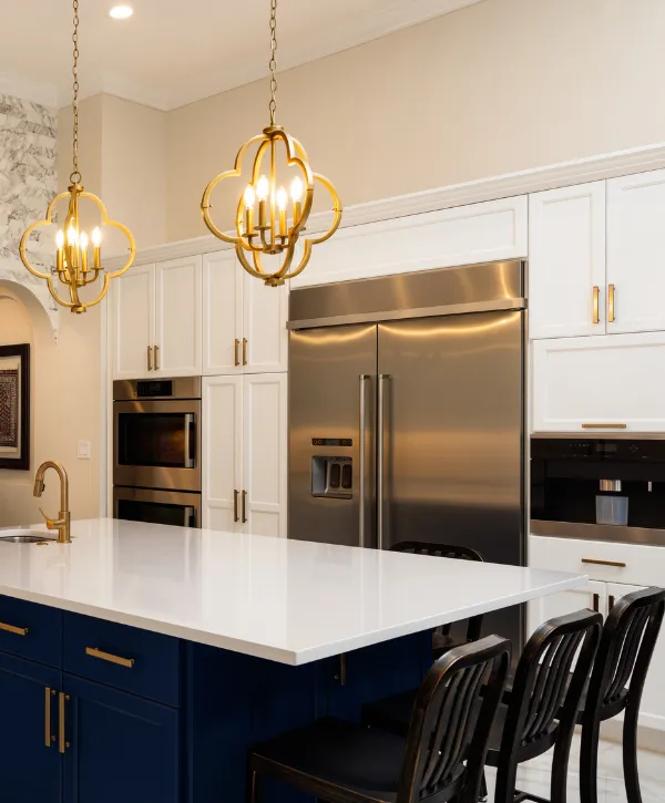 Luxury kitchen with gold pendant lights, white countertops, and stainless steel appliances.