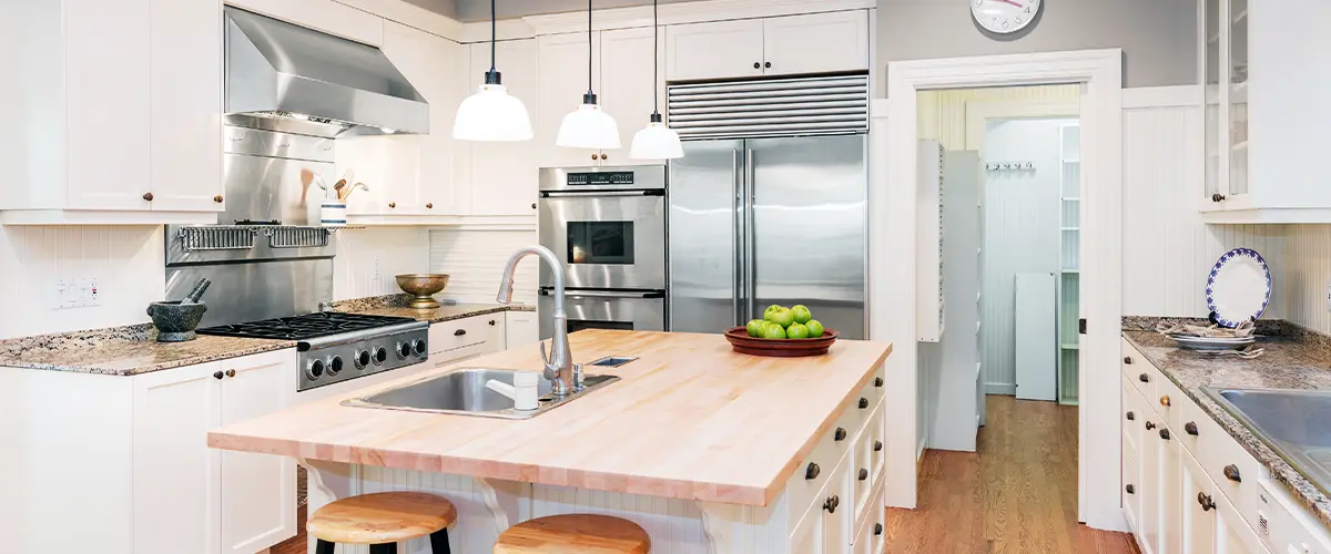 Traditional white kitchen with wood countertops, stainless steel appliances, and pendant lighting