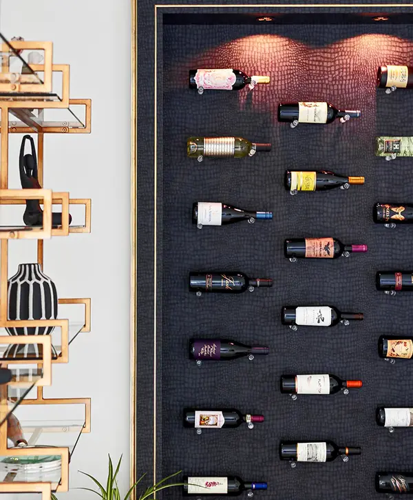 Wall-mounted wine display featuring bottles on a textured black background with adjacent artistic shelving