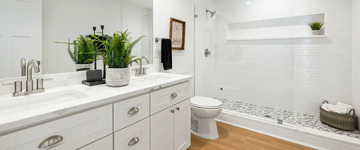 Modern bathroom with white cabinets, a dual vanity, walk-in shower, and wooden flooring, designed for luxury and functionality.