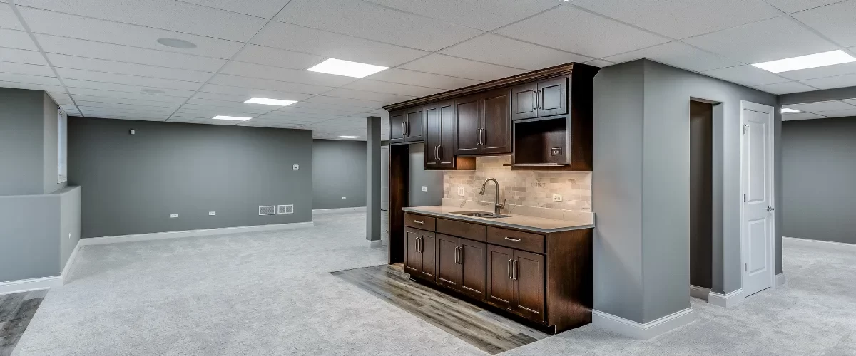 Modern basement renovation featuring a kitchenette with dark wood cabinets and recessed lighting.