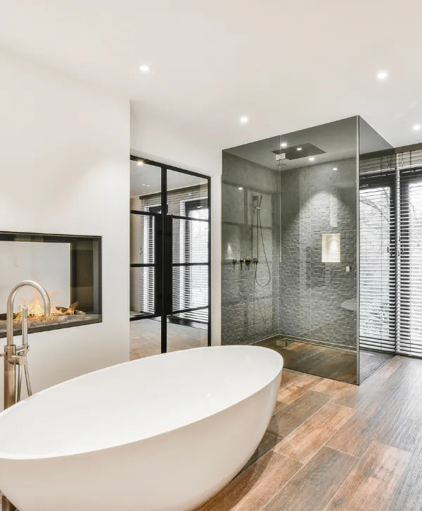 Contemporary bathroom featuring a freestanding bathtub, glass shower, and built-in fireplace.