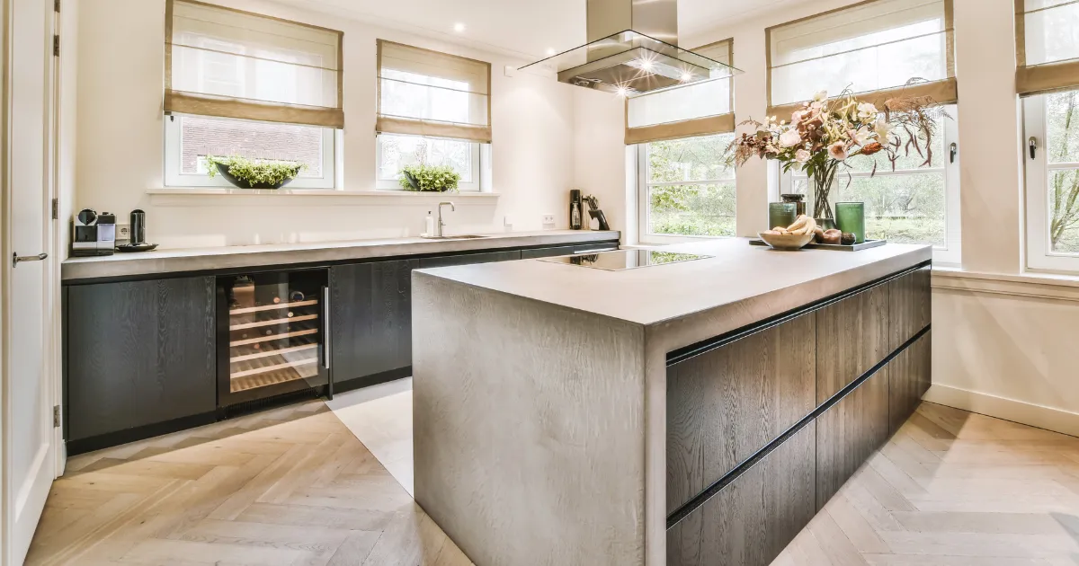 Elegant kitchen with neutral tones, a concrete island, and large windows providing natural light.