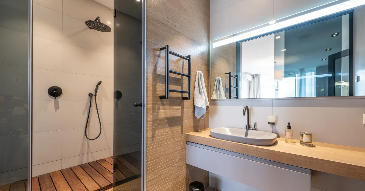 Modern bathroom with a walk-in shower, wooden vanity, and elegant lighting.