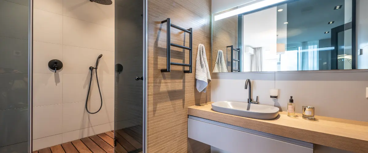 Warm-toned modern bathroom featuring a glass shower and wood accents