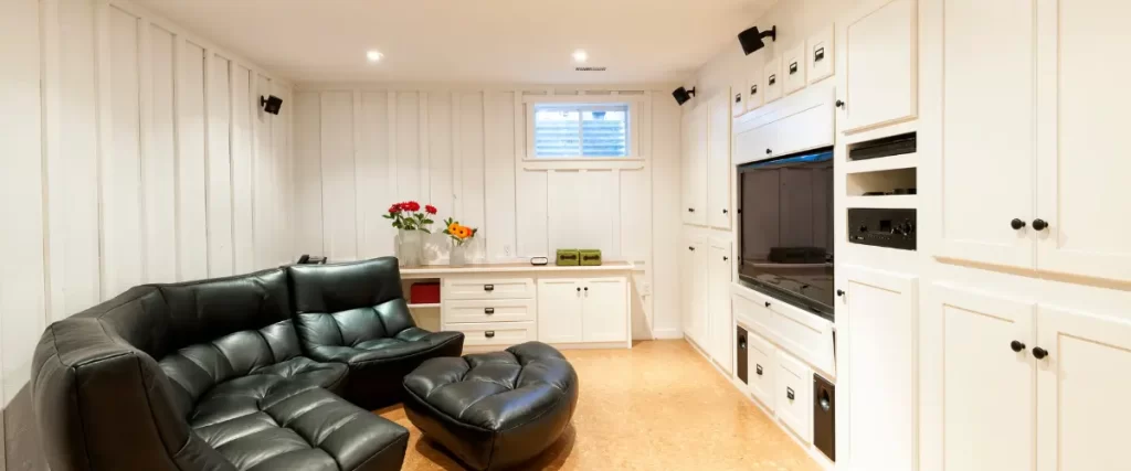 Compact basement media room with built-in cabinetry and leather seating