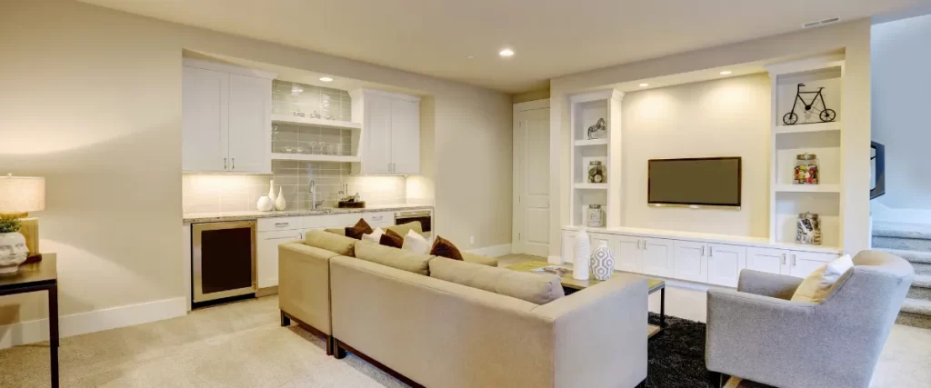 Cozy basement living area with beige sectional sofa and built-in white cabinetry