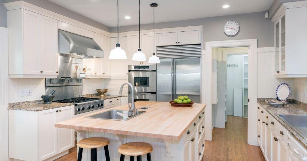 Classic white kitchen with butcher block island and stainless steel range