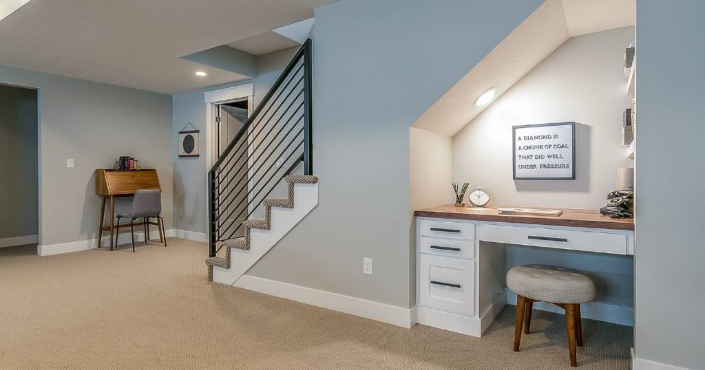 Finished basement with under-stair desk nook and modern railing