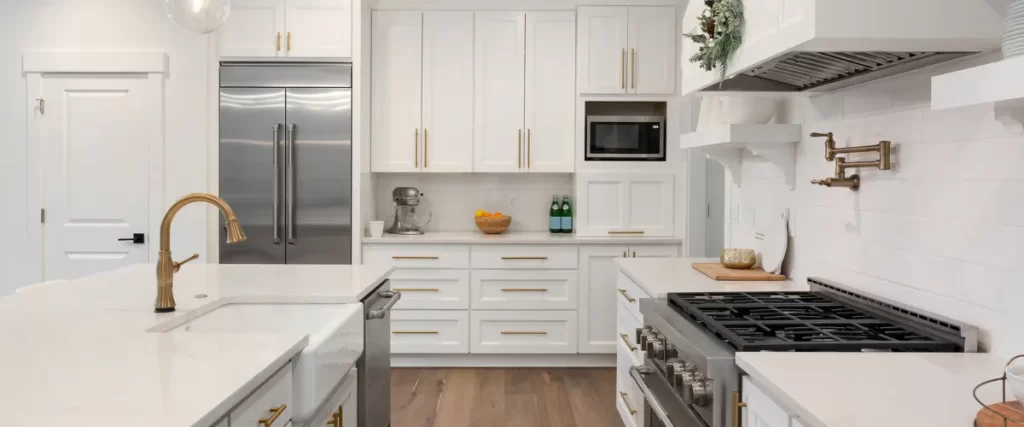 Modern white kitchen with gold fixtures and stainless steel appliances